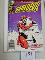 Front cover of Daredevil #182 comic book showing character in red costume hugging Elektra gravestone against purple cityscape background with white floating elements.