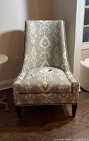 Front view of the custom upholstered chair showing patterned fabric, nailhead trim, and overall shape.