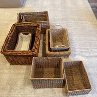 Nine assorted woven baskets in various sizes and shapes, displayed on carpet.