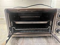 Front view inside toaster oven showing metal baking tray and oven rack.