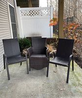 Three woven patio chairs arranged outdoors on patio slab, no cushions shown