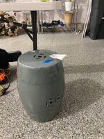 Photo of a green ceramic garden stool with a barrel shape, showing the top and side cutout patterns.