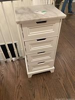 Front view showing 4 drawers with cutout handles and white wood framing under a marble top.
