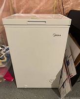 Front view of closed white chest freezer showing Midea logo and overall condition