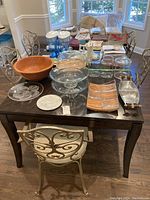 Photo of various serving ware on a dark wood table including wooden salad bowl, glass cake stand, glass cookie jars, wooden and glass cheese plates, metal divided tray, and glass pitchers in the background.