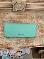 Blue Tiffany & Co. branded eyeglasses case on rustic wooden surface.