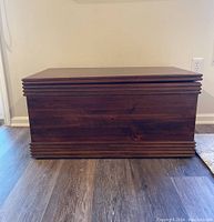 Front view of dark wood hope chest with molding detail and flat top surface.