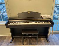 Front view of Yamaha Clavinova digital piano with bench and sheet music on music rest