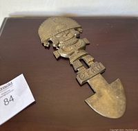 Close-up photo of the brass wall hanging showing the intricate human figure and arrowhead-shaped bottom.