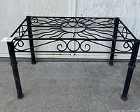 Front angle showing the table's four sturdy legs and decorative wrought iron scrollwork on the sides.