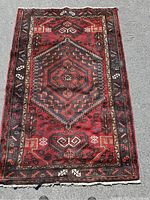 Top-down photo of vintage wool rug showing central diamond medallion and surrounding geometric designs