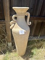 Full view of the large terra cotta vase showing overall shape and size outdoors against a wooden fence.