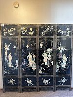 Full frontal view of six-panel black lacquer folding screen with inlaid scenes and gilt borders