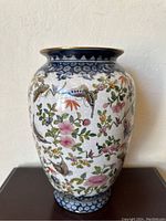 Front view of vintage Chinese porcelain vase showing floral and butterfly pattern with blue patterned rim and base.
