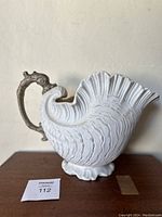 Side view of vintage shell shaped pitcher showing white textured shell design and ornate handle