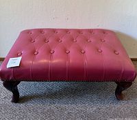 Front angled view of the vintage tufted ottoman showing button details and cabriole legs.