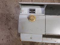 Close-up of yellow knob internal thermostat on white metal heater body, showing some dirt and wear.