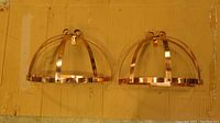 Two copper hanging racks in dome shapes viewed from front on cardboard background.