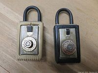 Front view of two real estate lock boxes, one beige and one black, with combination dials and labeled shackles.