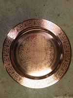 Close-up photo of the smaller tray showing intricate etched floral pattern on the rim and center