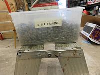 Plastic container labeled '3 1/4 FRAMING' filled with Ardox framing nails
