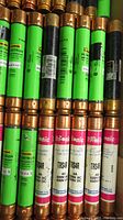 Close-up photo showing green labeled Cooper Bussmann dual element time delay fuses with copper ends and various amperage ratings.