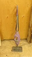 Front view of the purple carpet cleaner upright showing handle, cleaning head, and cord wrapped along the handle.