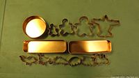 Full display of all copper cookie cutters and tins laid out on a green surface.