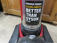 View of the vacuum base with power control dial and branding stating 'PROVEN POWER. CLEANS CARPETS BETTER THAN DYSON'.