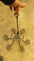 Top view of the black iron 7 candle holder showing the circular arrangement of candle platforms and the chain with the hook for hanging.