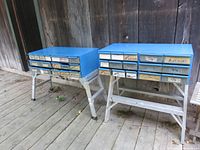 Two blue metal storage cabinets with multiple labeled drawers on white stands, visible labels include washers, bolts, anchors, rivets, and nuts.