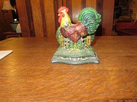 Colorful cast iron chicken napkin holder with painted rooster design on a wooden surface.