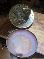 Close-up of the brass lid showing star-shaped perforations, hinge, and copper basin interior with patina.