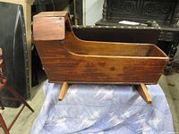 Side view of the wooden cradle highlighting original wood body with visible wear and replaced rockers.