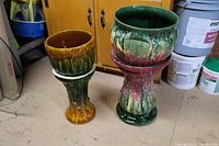 Two ceramic jardiniere planters on pedestal stands, showing sizes and color glazes.