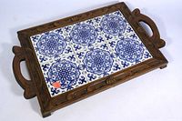 Full view of wooden serving tray with six blue and white ceramic tiles inset and carved wood handles.