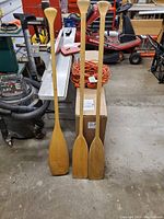 Three wooden canoe paddles standing upright showing full length and shape.