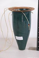 Front view of ceramic hanging pot showing tapered shape, dark green glaze, brown rim, and hanging cord