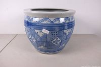 Blue and white porcelain planter with patchwork patterns and repaired ding on rim, front view