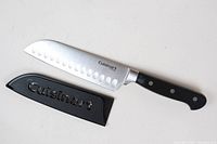 Full view of Cuisinart Santoku knife with black handle and sheath marked with Cuisinart logo.