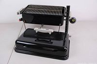 Full view of the portable Weber propane grill disassembled into body and lid with a ruler for scale and visible gas control knob.