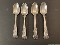 Top view of four antique sterling silver spoons laid flat, showing overall shape and design consistency.