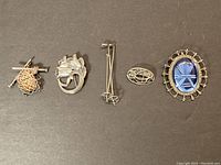 Five vintage sterling silver brooches laid out in a row showing full collection