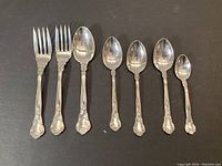 Photo showing all seven pieces of Birks sterling silver flatware arranged in a row on a dark background.
