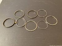 Overview of 8 sterling silver bangles laid flat showing varying shapes, sizes, and designs