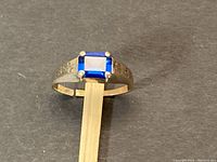 Front view of ring showing square blue stone in four-prong setting
