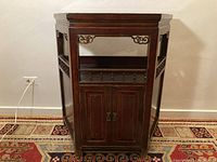 Full front view of antique Chinese wooden cabinet showing double-door front and decorative open shelf with carved details.