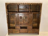 Front full view of the antique Chinese wooden shelf showcasing multiple open compartments, central cabinet with carved floral doors, and bottom drawers.