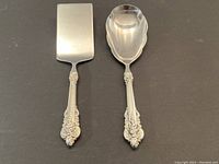 Photo showing flat serving spatula and serving spoon, each with ornate sterling silver handles.