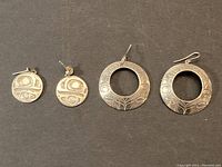 Both pairs of silver Haida earrings shown on black background for scale and detail.